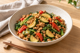 生成AIによる料理のイメージ。白い陶器の器に盛り付けた、大豆ミートとズッキーニ、赤パプリカ、青菜の炒め物。