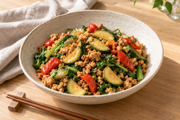 生成AIによる料理のイメージ。白い陶器の器に盛り付けた、大豆ミートとズッキーニ、赤パプリカ、青菜の炒め物。